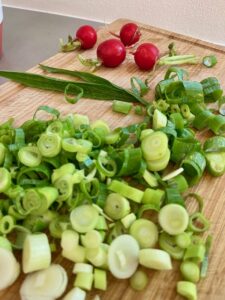 aufgeschnittener Lauch und im Hintergrund 3 rote Radieschen.